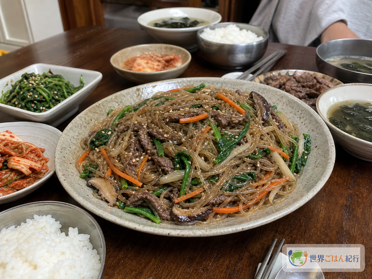 チャプチェ、キムチ、ご飯、韓国の小さな副菜を並べた家庭の食卓
