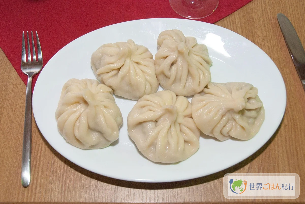 ジョージア料理の伝統的な食卓。ハチャプリ、ヒンカリ、サラダ、ワインが並ぶ