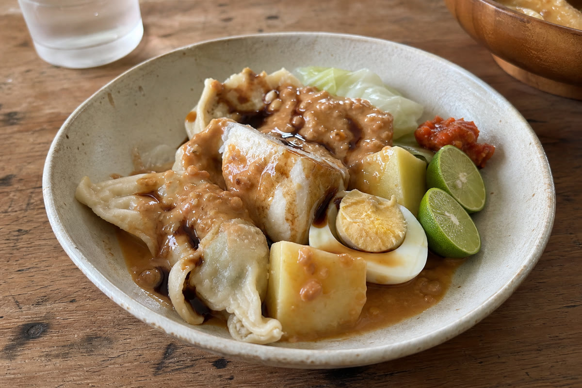 蒸した魚団子、豆腐、キャベツ、じゃがいも、卵にピーナッツだれをかけたインドネシアのシオマイ