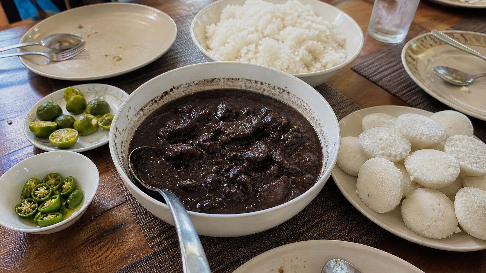 ディヌグアン、白ごはん、プト、ライム、青唐辛子を並べたフィリピン家庭の食卓