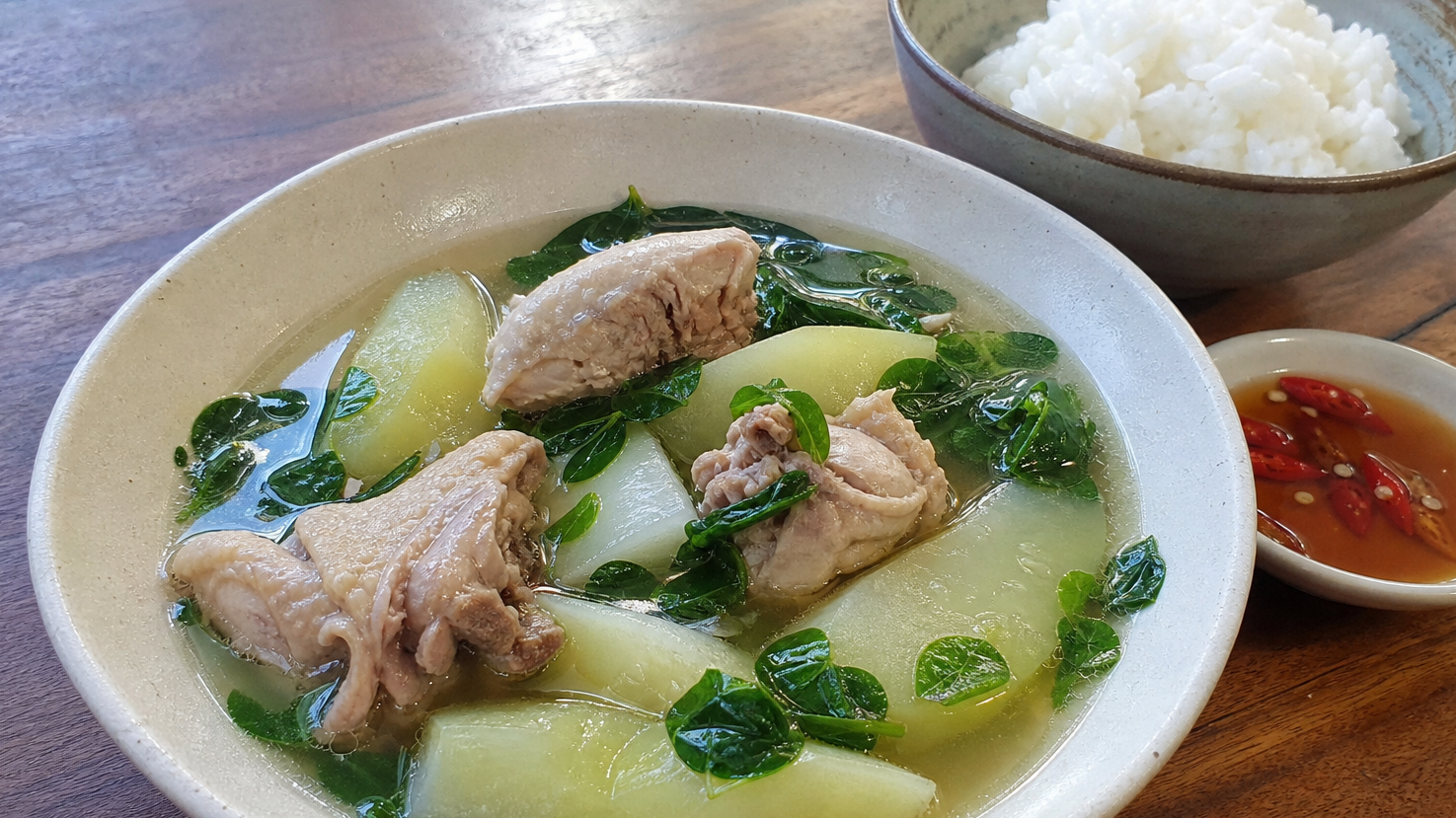 ご飯とパティスを添えたフィリピンのティノラ。澄んだしょうがスープに骨付き鶏、青パパイヤ、青菜が入っている
